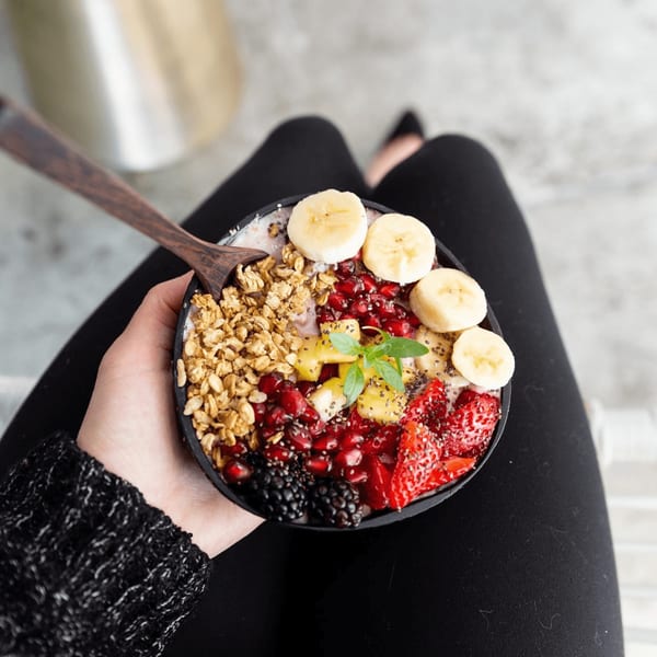 Overhead view of a person holding a Sustainabowl with granola, fruit, and chia seeds.