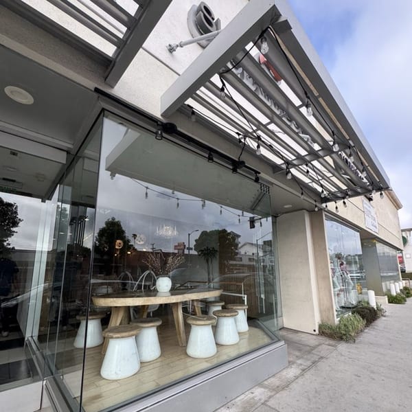 Exterior view of a modern restaurant with large glass windows and an outdoor seating area.